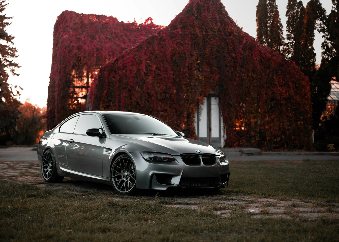 BMW M3 E92 grise devant une façade de lierre automnal — évaluer une voiture de prestige d'occasion