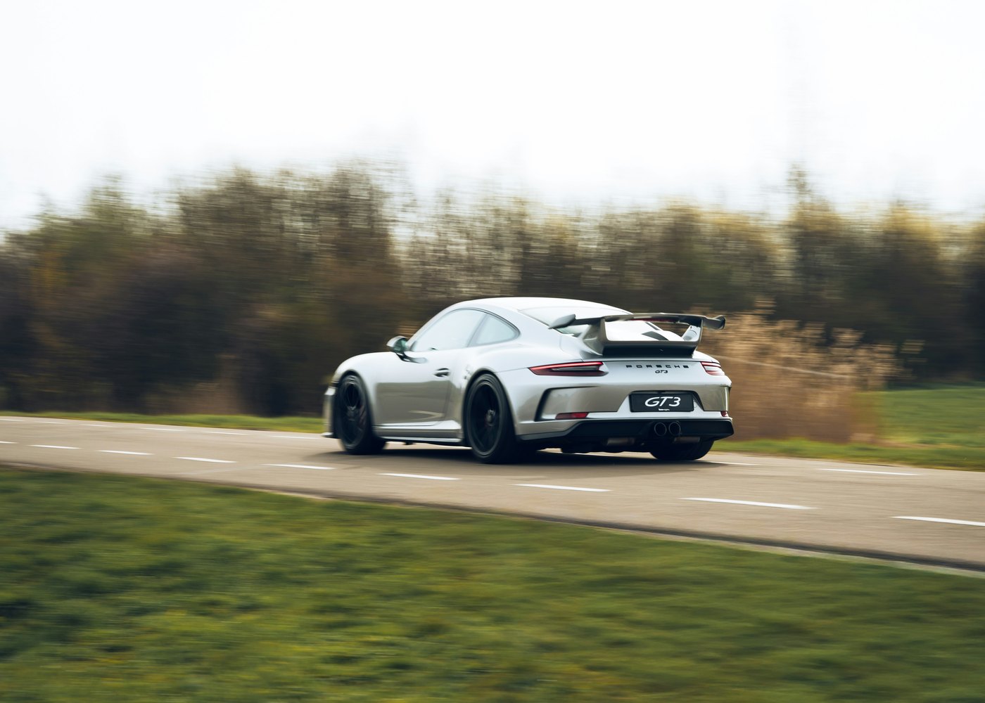 Porsche 911 991.2 GT3 grise en mouvement sur route, trois quarts arrière